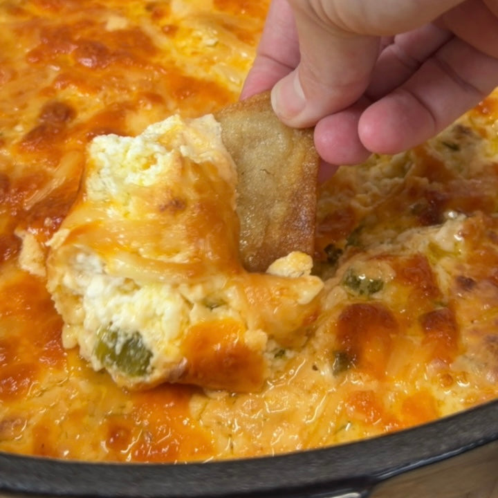 Jalapeno Popper Dip being scooped on a tortilla